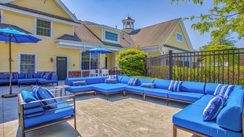 Outdoor patio and grills with blue couches and umbrellas at Windsor Ridge at Westborough, Westborough, MA